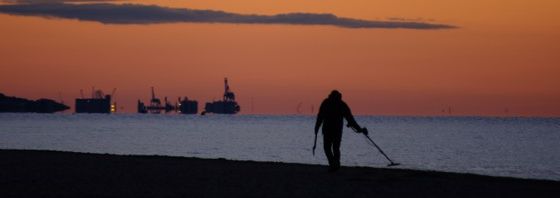 Man On Beach Using Detector On The Beach Using A Metal Detector At Night